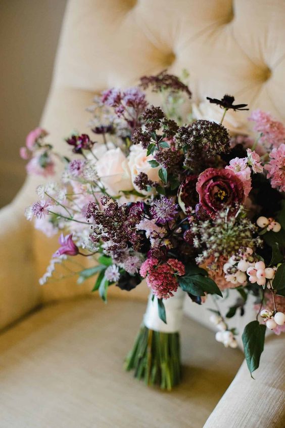 A lovely textural wedding bouquet with plum colored, neutral, deep purple and pink blooms, berries and leaves is wow