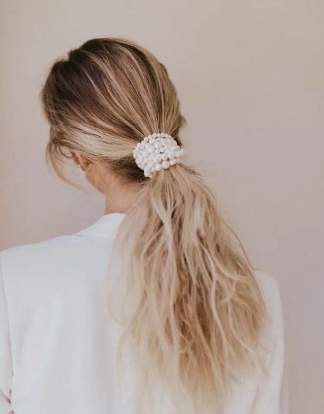 a low and messy ponytail wrapped up in pearls is a chic idea for a modern or minimalist bride
