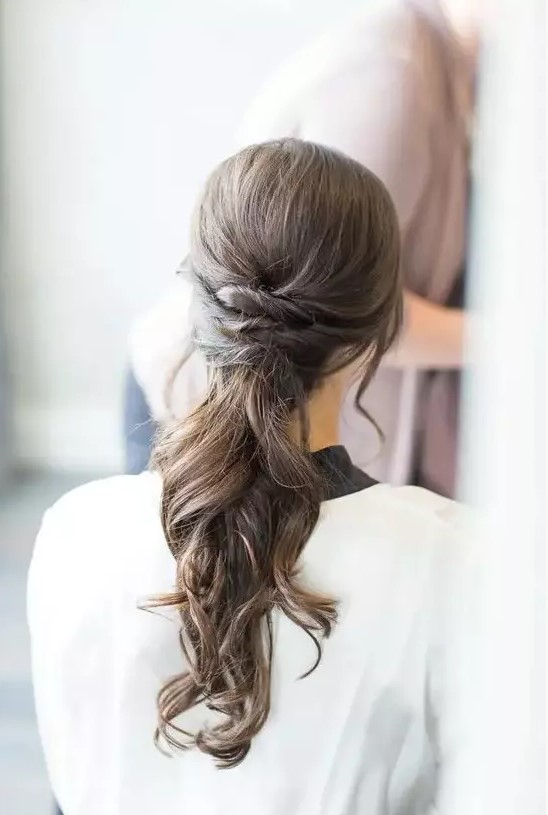 a low ponytail with twists and waves for a modern beach bride, it's a stylish solution for many weddings, and it can be worn with long or medium-length hair