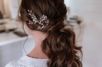 a low wavy ponytail with a twisted top and locks drown, with an embellished headpiece is a lovely idea