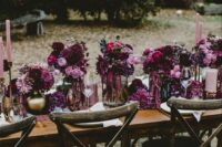 a lush and bold wedding tablescape with lots of plum-colored, pink and fuchsia blooms and pink candles is a very decadent idea for the fall
