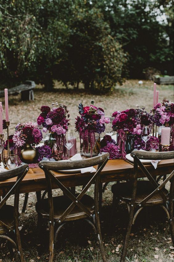A lush and bold wedding tablescape with lots of plum colored, pink and fuchsia blooms and pink candles is a very decadent idea for the fall