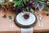 a lush fall woodland wedding table setting with jewel-tone blooms and herbs and pinecones