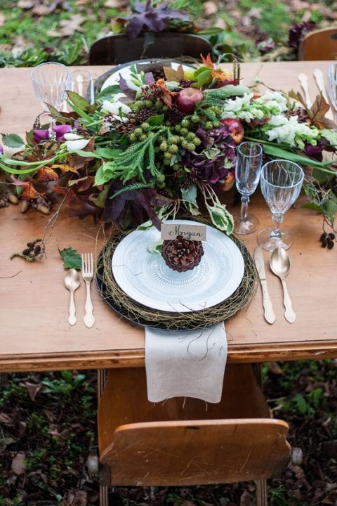 a lush fall woodland wedding table setting with jewel-tone blooms and herbs and pinecones