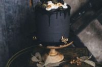 a matte black wedding cake with black drip, cream, gilded blackberries and black chocolate shards is a stylish idea for a moody fall or Halloween wedding