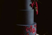 a matte black wedding cake with painted red blooms and fresh ones on top plus greenery is a refined idea for a fall decadent wedding