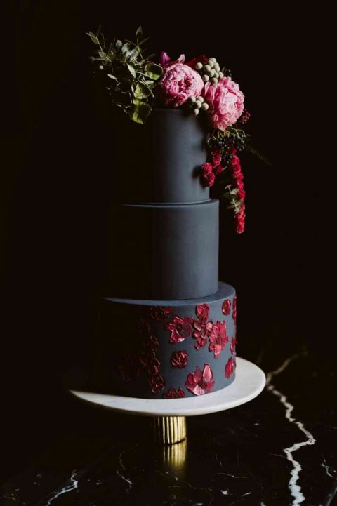 a matte black wedding cake with painted red blooms and fresh ones on top plus greenery is a refined idea for a fall decadent wedding