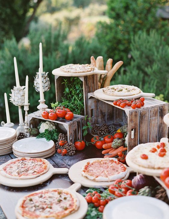 a mini pizza bar with various fresh veggies and herbs and lots of kinds of pizza for a Tuscany wedding