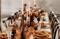 a modern Thanksgiving tablescape with wooden candleholders and tall candles, bold floral arrangements, mellow yellow linens