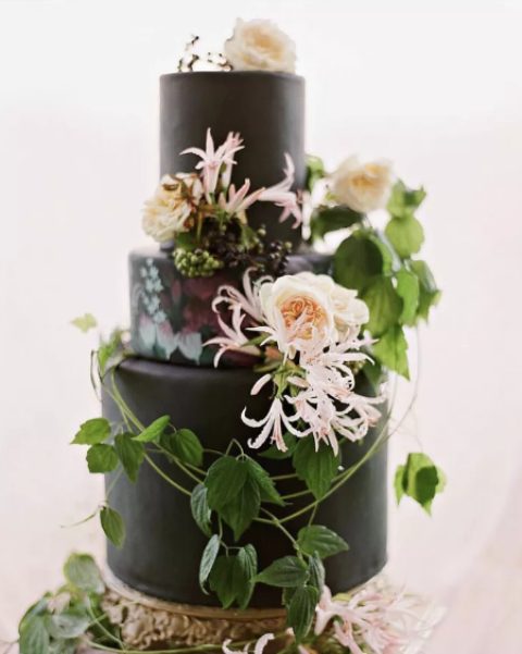 a plain black wedding cake with painted blooms, fresh blush flowers and greenery is a very chic and cool idea for a modern wedding