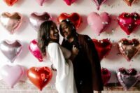 a pretty Valentine wedding pic with a heart balloon wall, bride-to-be wearing red polka dot shoes