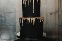 a refined and contrasting matte black wedding cake with gold dripping is a stylish modern idea, suitable for a Halloween or minimal wedding, too