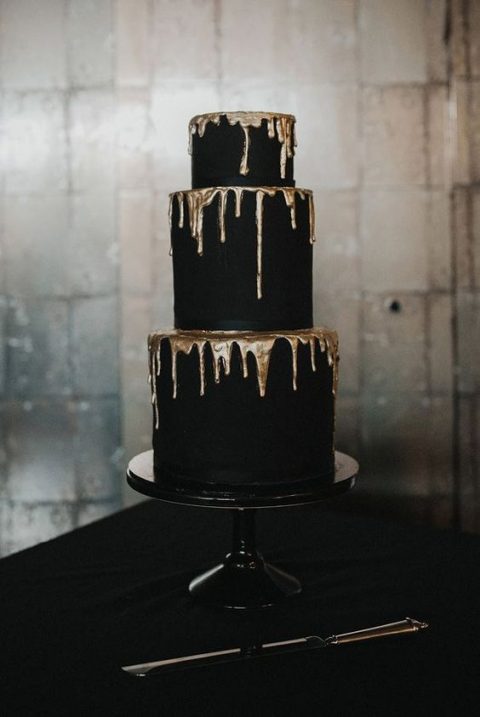 a refined and contrasting matte black wedding cake with gold dripping is a stylish modern idea, suitable for a Halloween or minimal wedding, too
