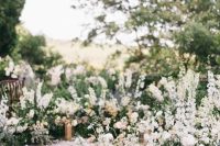 a romantic Tuscany wedding ceremony space with a semi-circular altar with lots of greenery and white and blush blooms