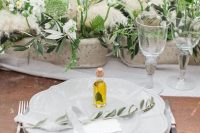 a romantic Tuscany wedding tablescape with potted blooms and leaves, pampas grass and olive oil favors