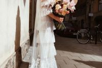 a romantic tiered ruffle wedding dress, short sleeves, a train and a veil for a whimsical bridal look