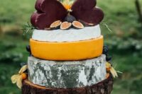 a rustic cheese tower on a thick wooden piece with herbs and figs plus a duo of dark heart-shaped cheese pieces is a fantastic idea for a rustic wedding
