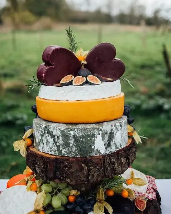 a rustic cheese tower on a thick wooden piece with herbs and figs plus a duo of dark heart shaped cheese pieces is a fantastic idea for a rustic wedding