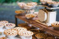 a rustic pie table with mini pies on stands, a wooden shelf with pies and mini scales looks super cute