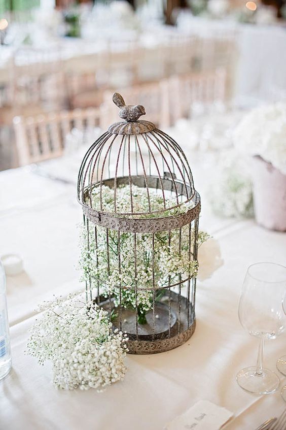 a shabby chic birdcage with a bird on top and some baby's breath is a cool idea for a wedding with a vintage feel