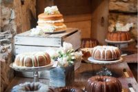 a simple and cool rustic dessert table of wood, crates and simple glass stands, with white blooms and cakes