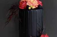 a small matte black wedding cake with black drip, berries, red and pink blooms, feathers and twigs is a beautiful and modern idea to rock