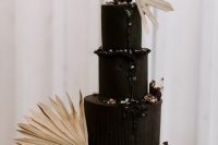a sophisticated and inspiring black wedding cake with berries, black drip, dried fronds and glitter will be a bold solution for a moody boho wedding