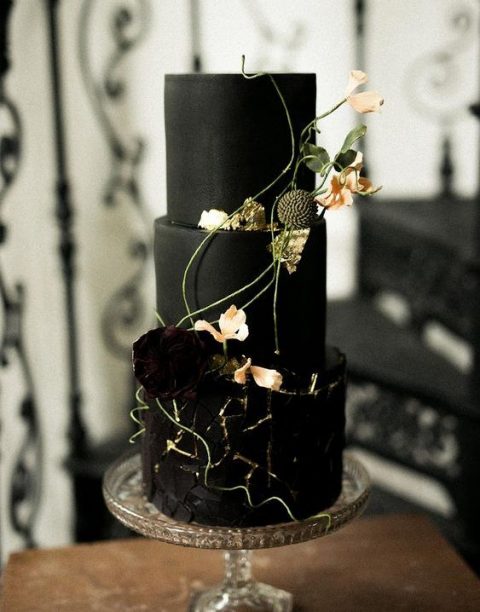 a sophisticated black wedding cake with a textural tier, dark and blush blooms and some greenery is a beautiful and refined idea for a Halloween wedding