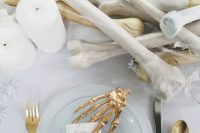 a stunning all-white tablescape with faux bones and spiders and gilded touches will be a refined and cool idea for a Halloween bridal shower