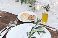 a stylish Tuscany wedding tablescape with neutral linens, neutral blooms and greenery, olive oil as favors and fresh bread