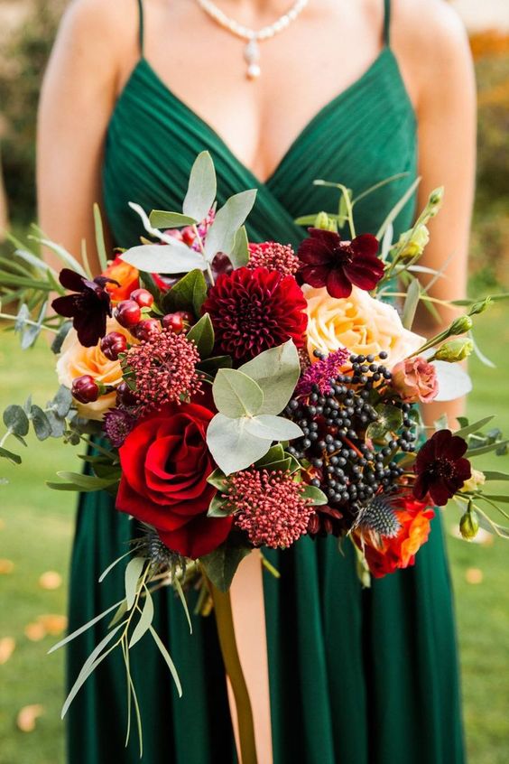 a super bold fall wedding bouquet of bright and dark blooms, berries, thistles, various kinds of foliage and greenery