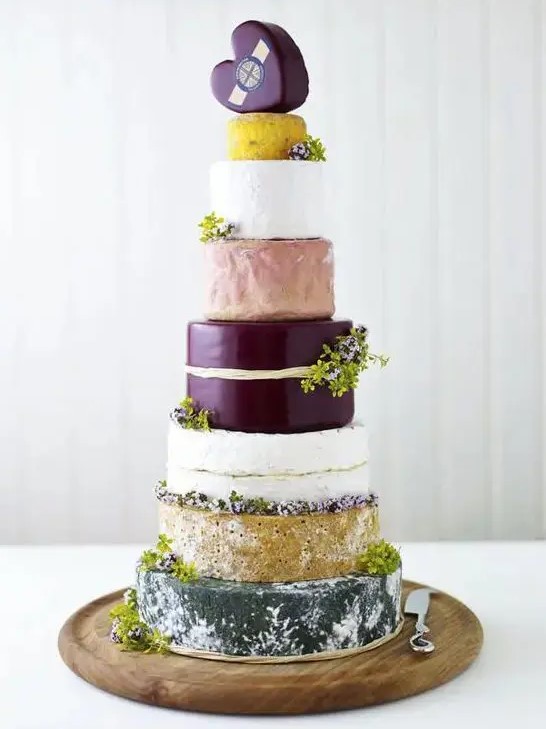 a super tall cheese tower with greenery and a heart shaped cheese piece on top is a gorgeous idea for a modern wedding