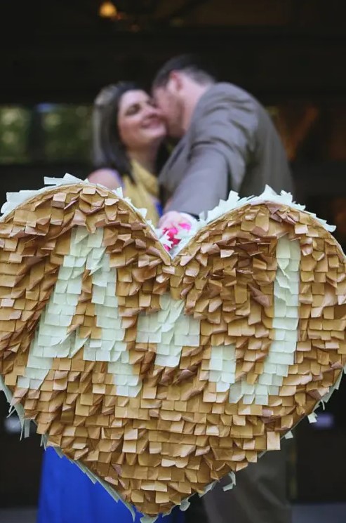 a tan and white fringe heart shaped pinata as a creative wedding guest book, with monograms for more personalization is a lovely idea