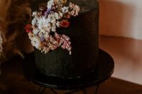 a textural black wedding cake with colorful and neutral dried blooms, berries and burgundy macarons on top is a gorgeous idea for the fall