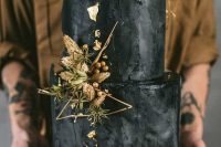 a textural black wedding cake with gold leaf, dried whear, gold twigs and berries plus a raw edge on top is a fabulous idea to try