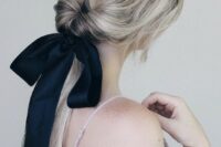 a twisted low ponytail with a sleek top and a black ribbon bow that adds drama to this cute hairstyle
