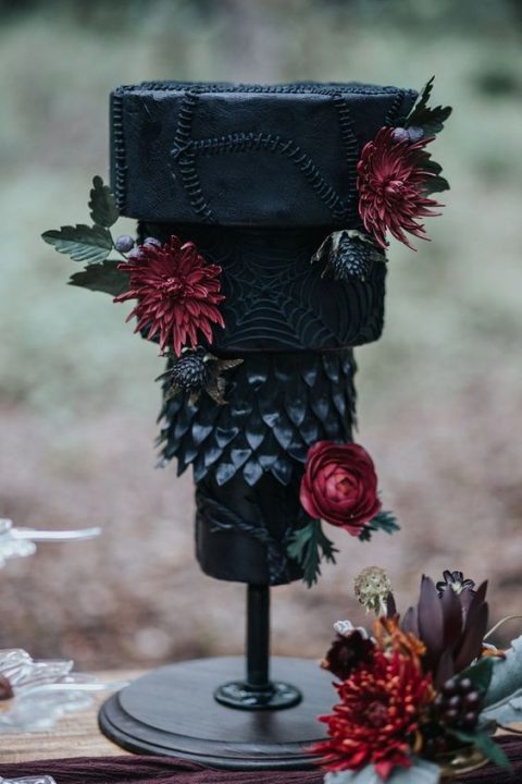 a unique haunted Halloween wedding cake with textural tiers and red blooms and green leaves is a statement idea for a Halloween wedding