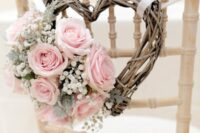 a vine heart-shaped wreath with baby’s breath, pink roses and pale leaves is a cool rustic chair decoration