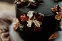 a vintage-inspired black wedding cake with neutral and brown sugar blooms on top is a beautiful and creative idea