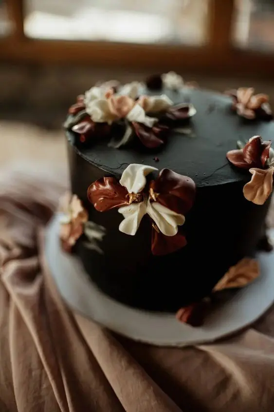 a vintage-inspired black wedding cake with neutral and brown sugar blooms on top is a beautiful and creative idea