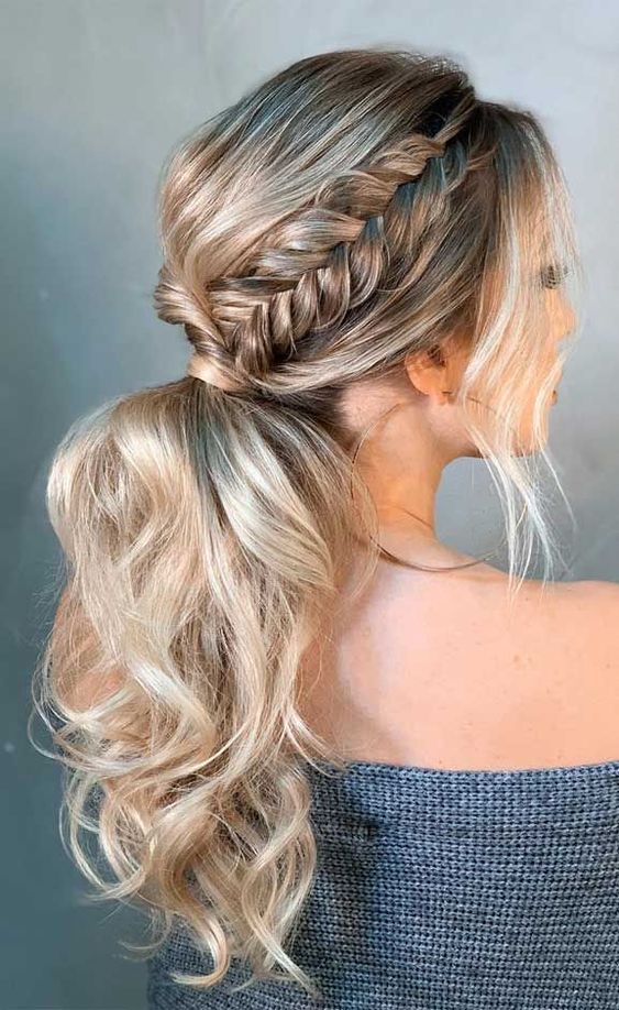 a wavy low ponytail with a bump on top, a braided halo and locks framing the face is a nice boho or rustic wedding hairstyle