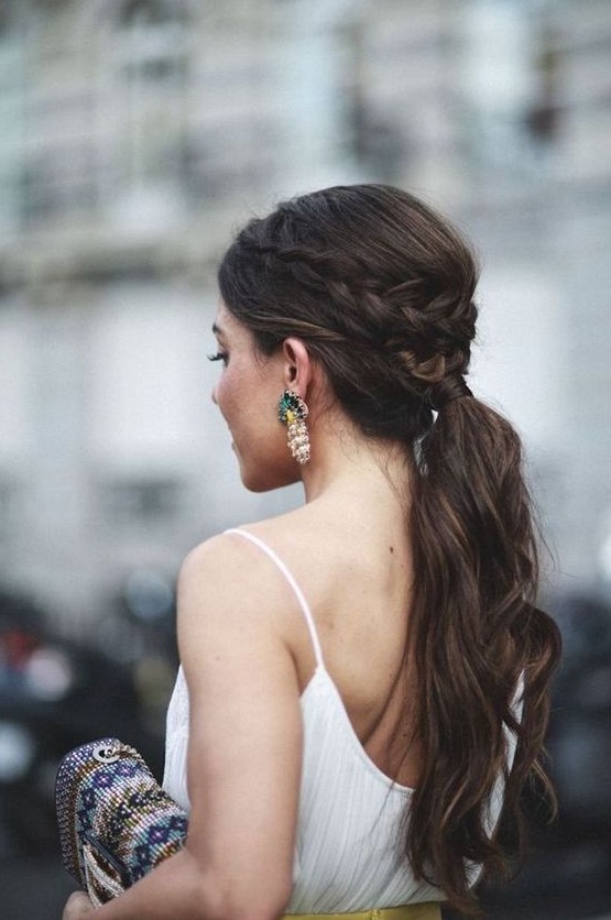a wavy ponytail with a bump and a braided halo for a casual and modern bride