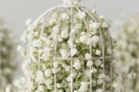 a white birdcage with baby’s breath and a bird on top is a cool idea for a wedding, it looks sophisticated and airy