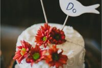 a white patterned wedding cake with bold blooms and plywood bird cake toppers is a cool and fresh idea