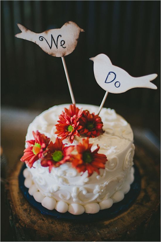 a white patterned wedding cake with bold blooms and plywood bird cake toppers is a cool and fresh idea