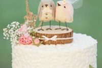 a white textural wedding cake with a tree slice and bird toppers, with baby’s breath and pink roses is cool and cute
