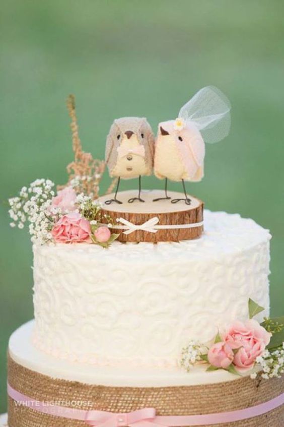a white textural wedding cake with a tree slice and bird toppers, with baby's breath and pink roses is cool and cute