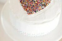a white wedding cake with a colorful conetti heart on top is a lovely and beautiful idea for a Valentine wedding