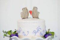 a white wedding cake with lilac patterns and fun burlap love bird cake toppers is an amazing idea for a wedding