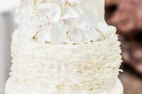 a white wedding cake with ruffle and sleek tiers, with love bird cake toppers is a cool idea for a wedding